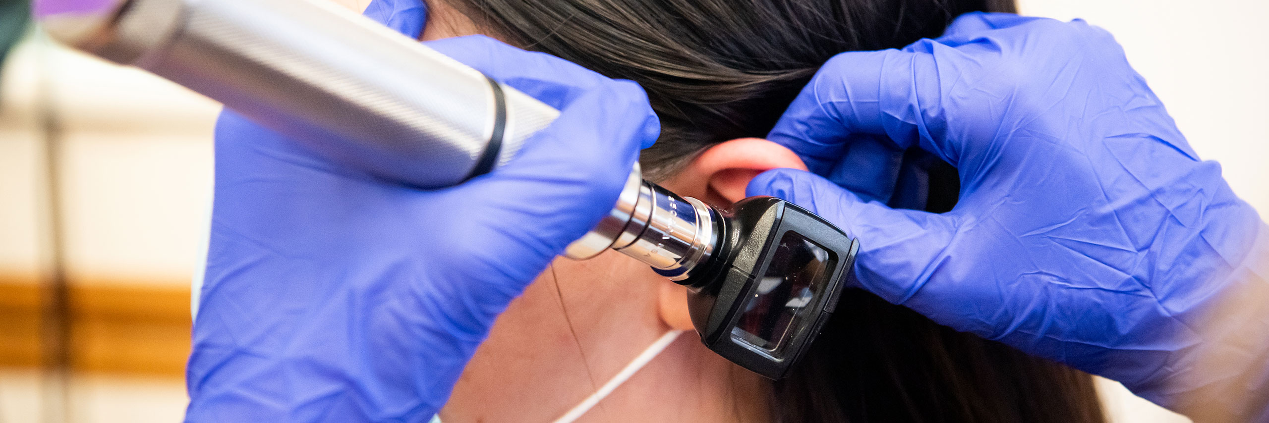 College student at a communication science and disorder institute conducting an ear exam.